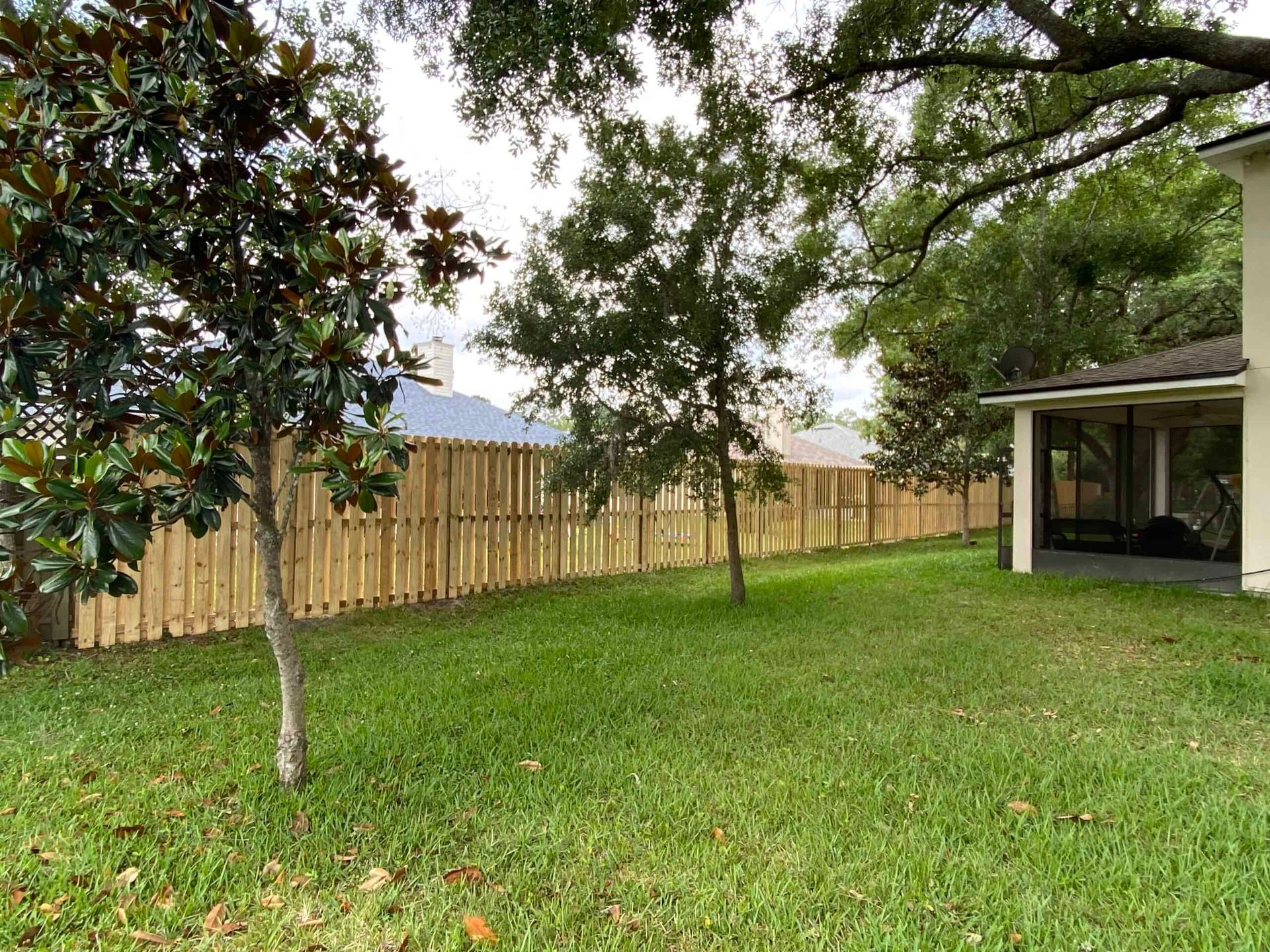 A backyard with a wooden fence and trees.