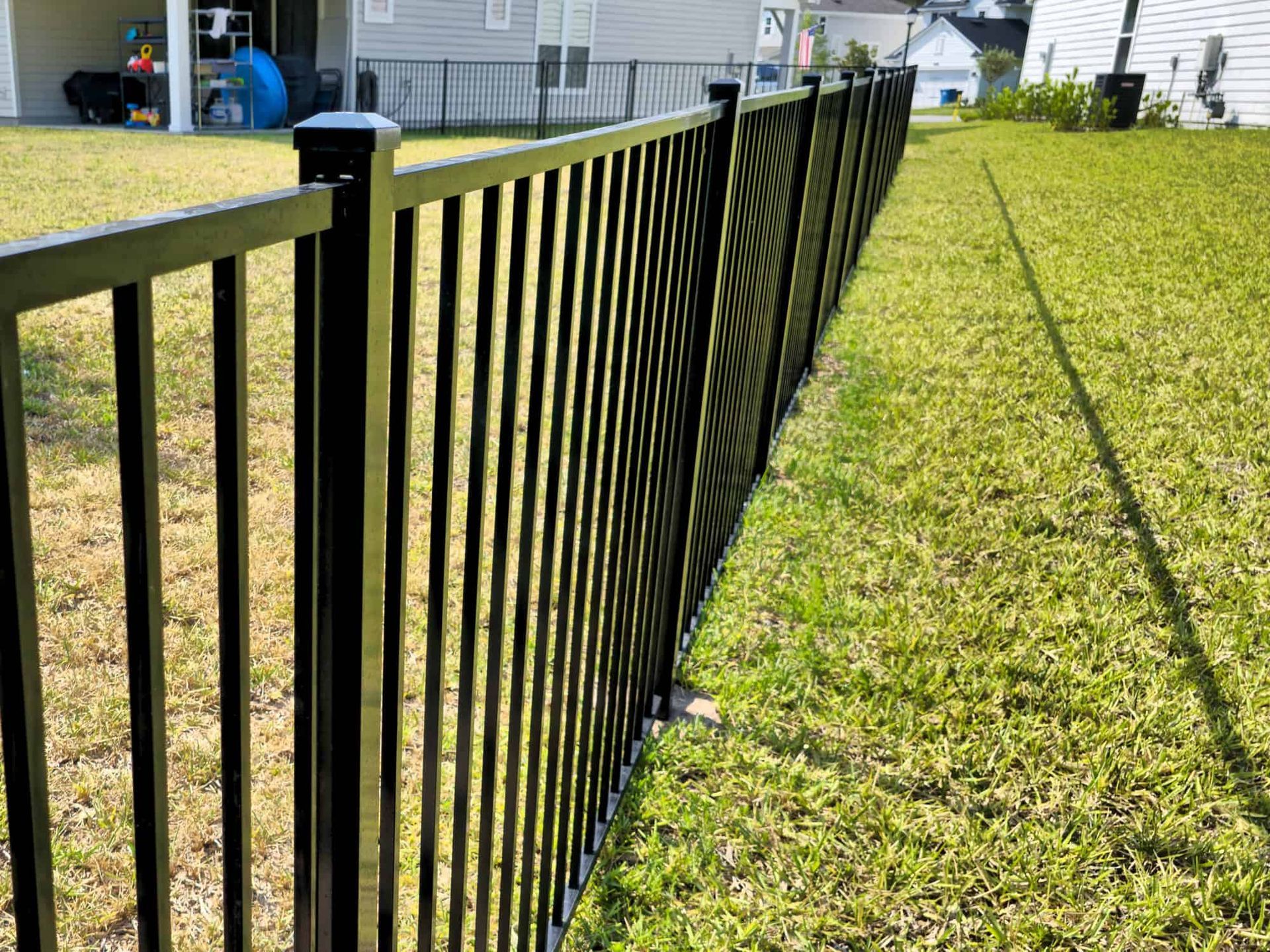 A black metal fence surrounds a lush green yard.