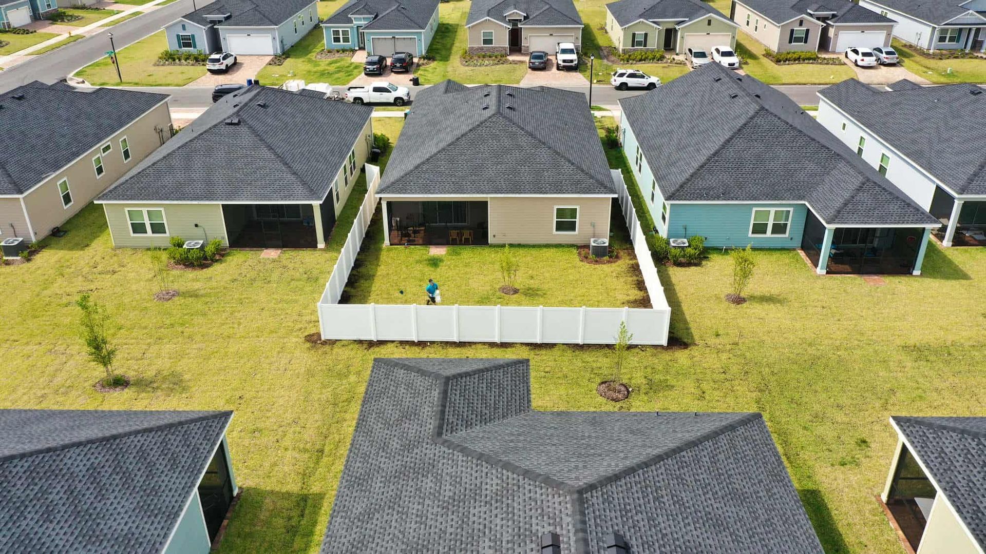 An aerial view of a residential neighborhood with houses and a white fence.