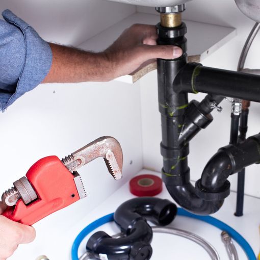 A man is fixing a sink with a wrench