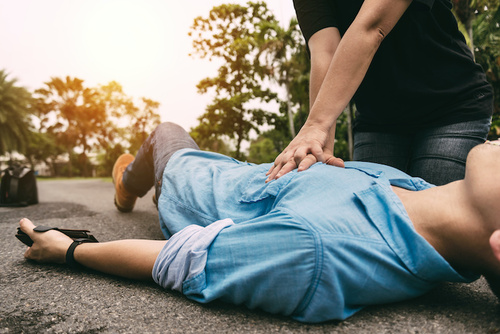 person giving first aid cpr to a man lying on the side of the road