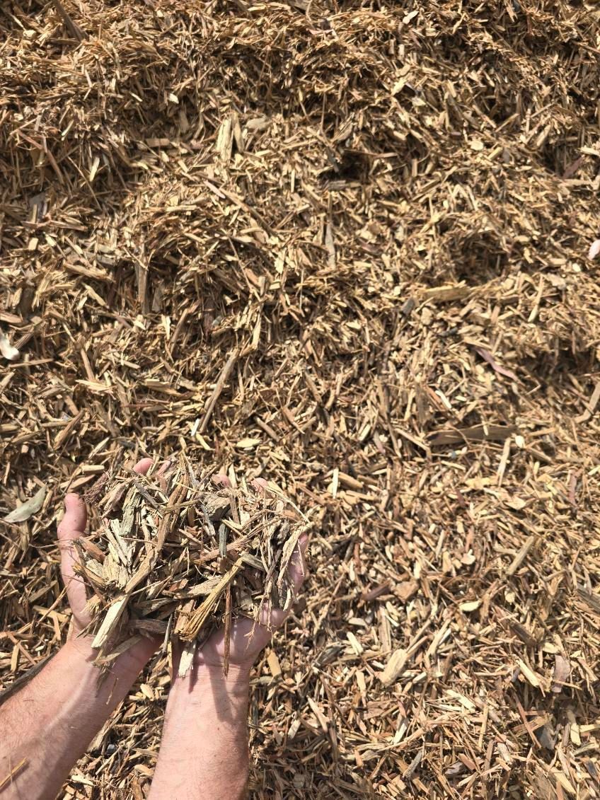 Hands Holding a Pile of Light Brown Mulch — BVN Landscape & Steel Supplies in St Georges Basin, NSW