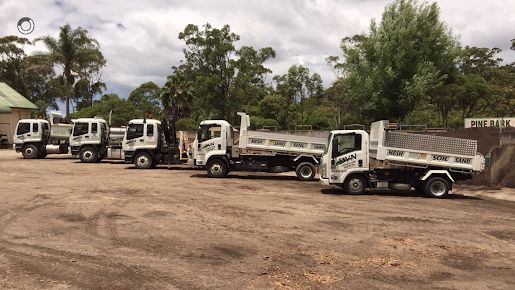 A Row of Dump Trucks Are Parked in A Dirt Lot — BVN Landscape & Steel Supplies in Vincentia, NSW