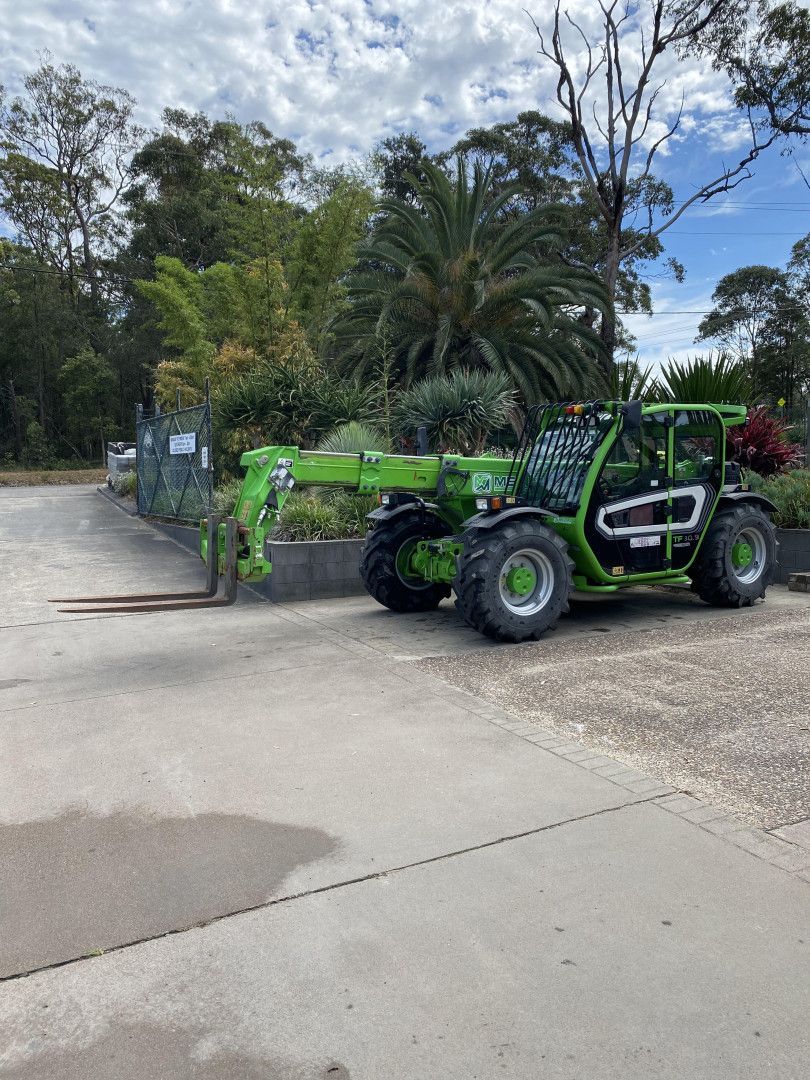 Green Telehandler With Extended Forks on Pavement — BVN Landscape & Steel Supplies in St Georges Basin, NSW
