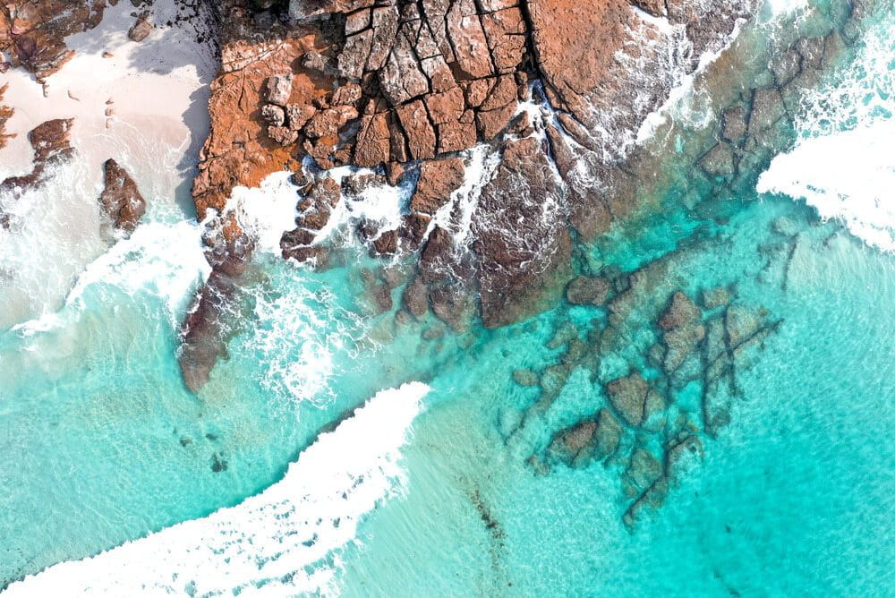 Aerial View of Turquoise Waves Washing Over a Rocky Shoreline — BVN Landscape & Steel Supplies in Vincentia, NSW