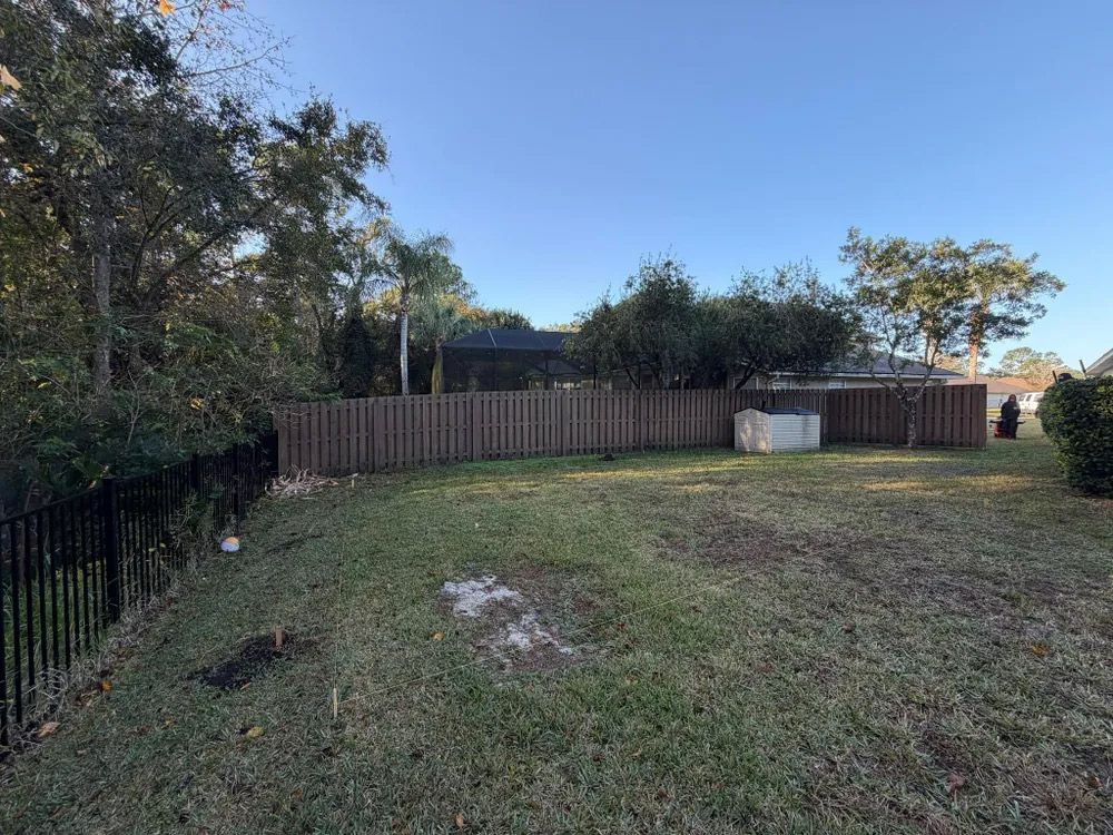 A grassy backyard with a brown wooden fence