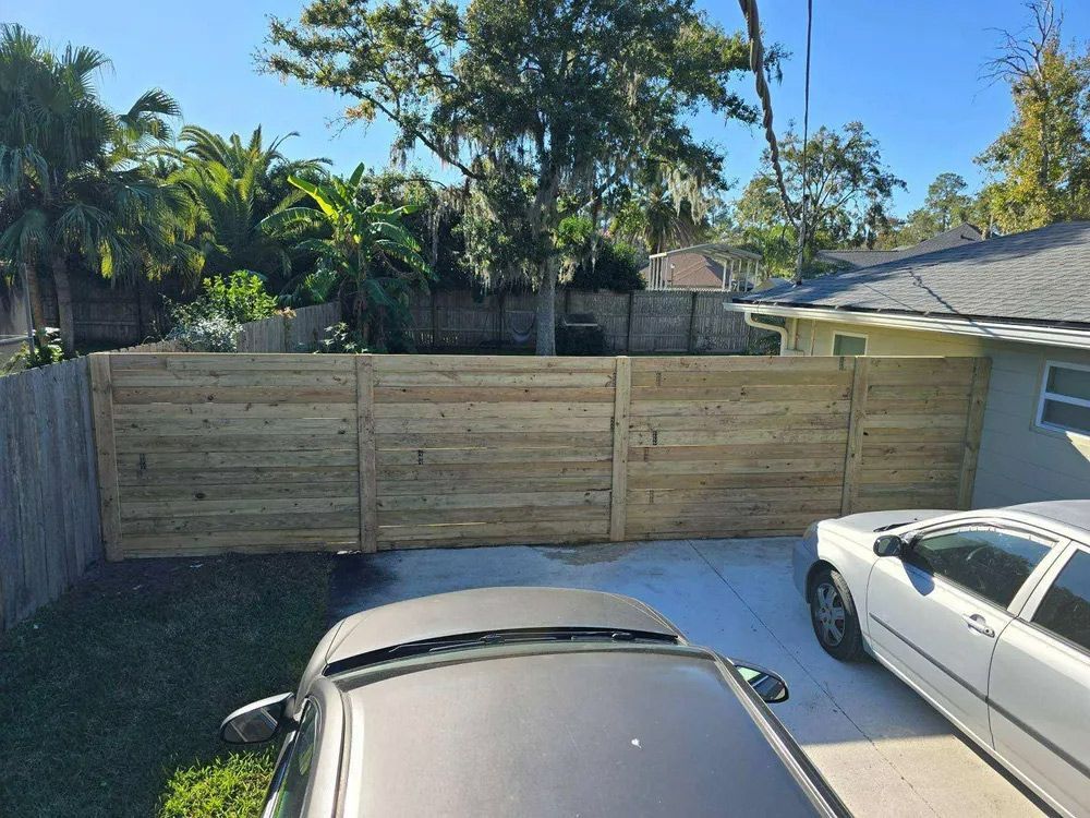 Wooden fence installed across a concrete driveway