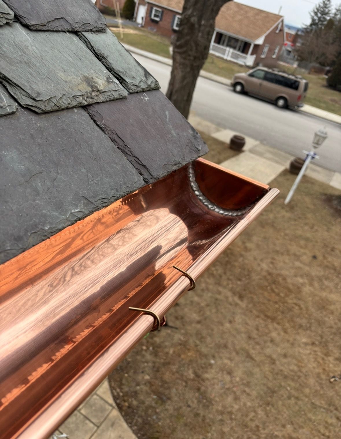 A copper gutter is attached to the roof of a house.