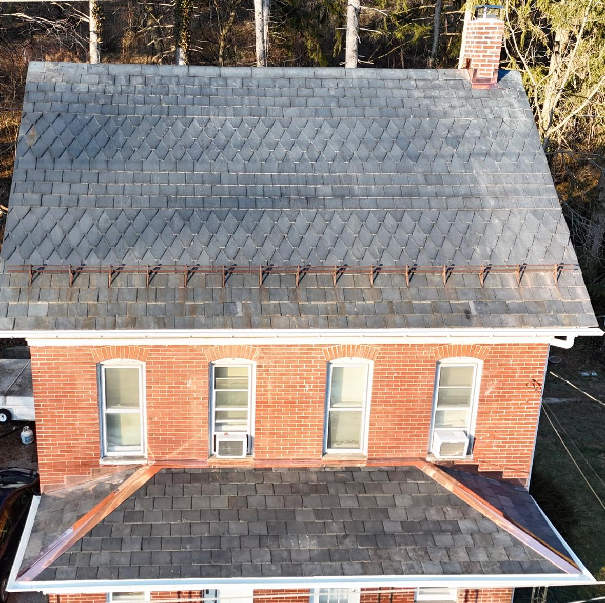 An aerial view of a brick house with a black roof