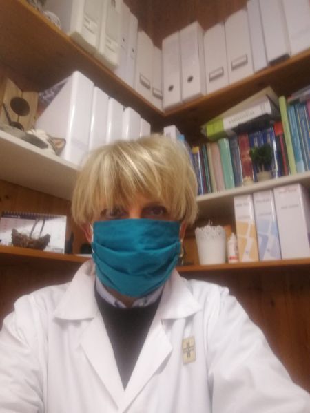 Una donna in camice da laboratorio che indossa una maschera blu