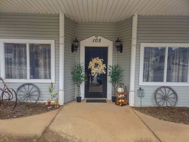 The front door of a house with a porch and plants in front of it.