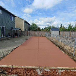 A concrete driveway is being built in the backyard of a house.