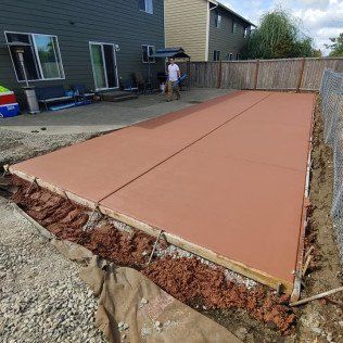 A concrete driveway is being built in the backyard of a house.