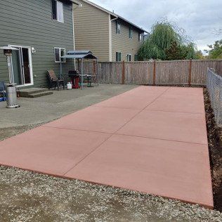 A large red concrete driveway in front of a house.