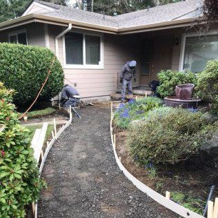 A couple of men are working on a walkway in front of a house.