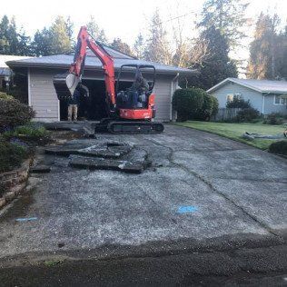 A small excavator is sitting in front of a house.