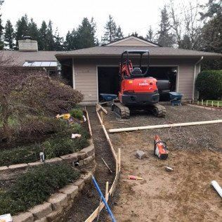 A small orange excavator is parked in front of a house.