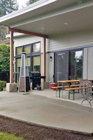 A patio with tables , benches and a heater in front of a house.