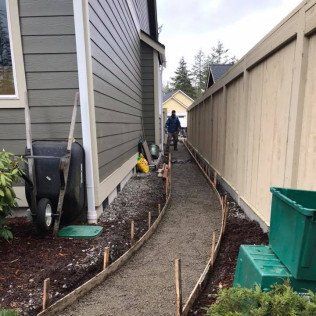 A man is walking down a sidewalk next to a house.