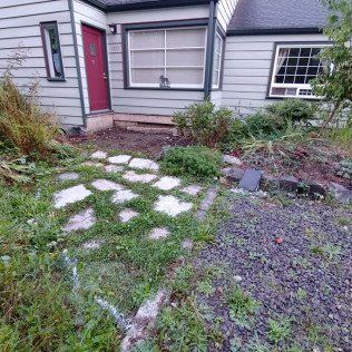 A white house with a red door and a stone walkway in front of it.