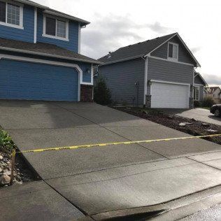A blue house with a white garage door is next to a gray house with a white garage door.