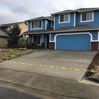 A blue house with a concrete driveway in front of it.
