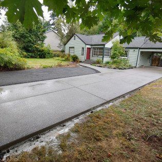 A concrete driveway leading to a house in a residential area.