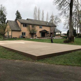 A man is standing on a concrete platform in front of a large house.
