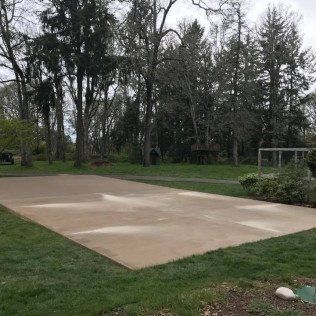 A large concrete dance floor in a park with trees in the background.