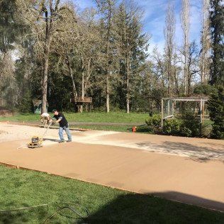 A man is standing on a concrete driveway in a park.