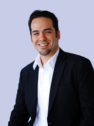 A man in a suit and white shirt smiles for the camera