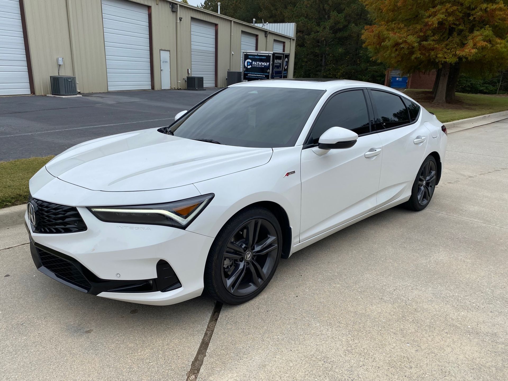 A white car is parked on the side of the road in front of a building.
