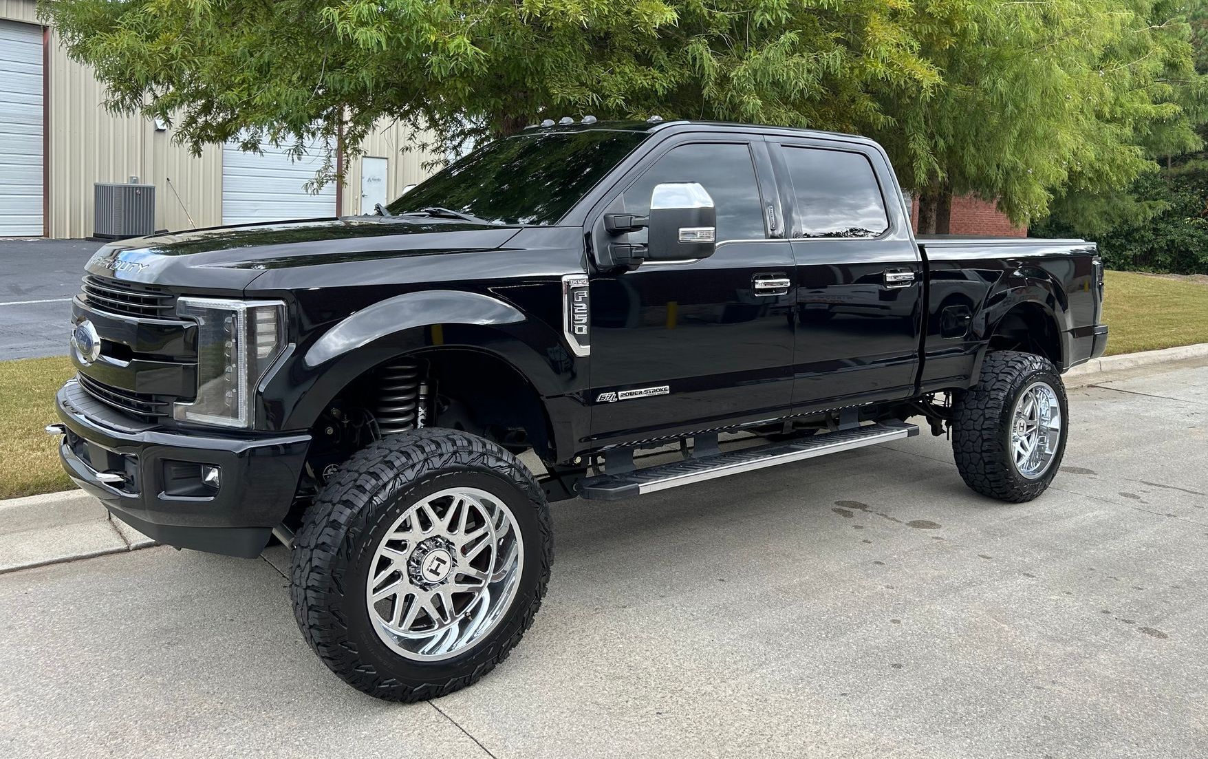 A black ford truck is parked on the side of the road.