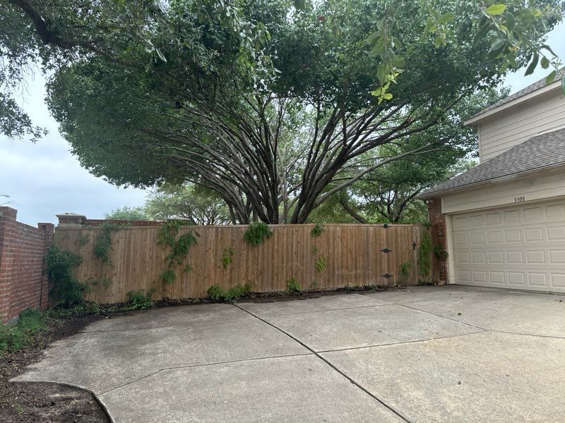 A wooden fence surrounds a driveway in front of a house.