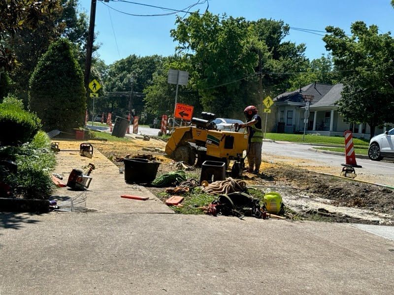 A yellow stump grinder is being used to remove a tree stump