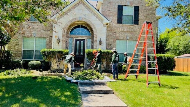 A group of men are working in front of a large brick house.