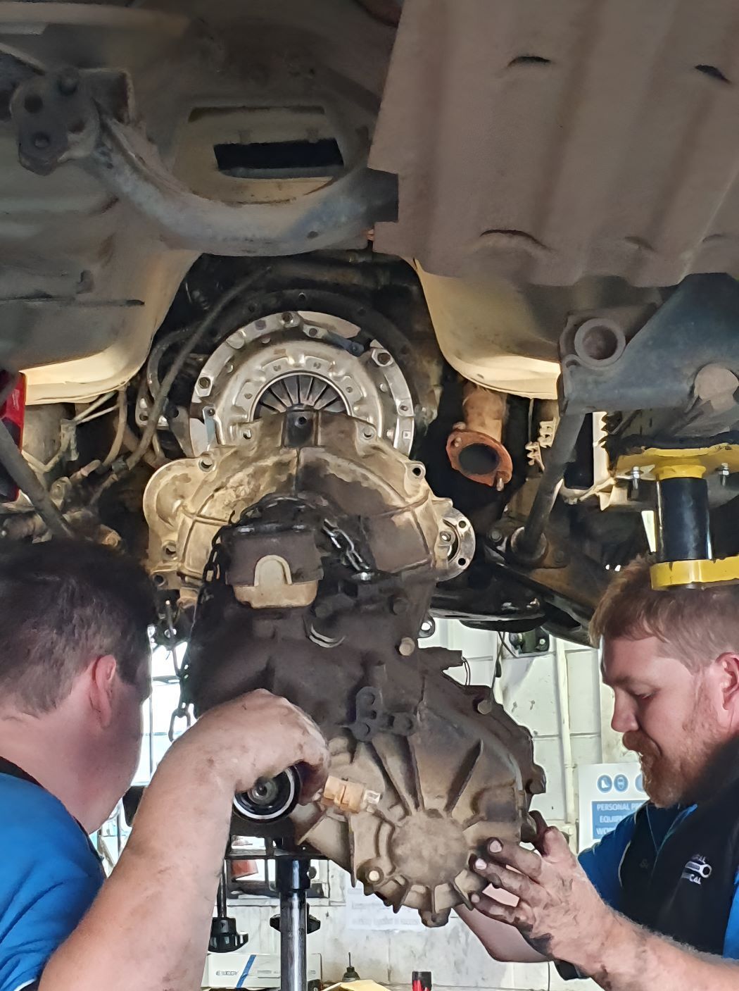 Two Men Are Working on the Underside of a Car — SMK Rural & Mechanical Pty Ltd in Rockhampton City, QLD