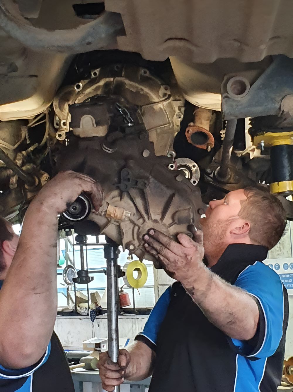 Two Men Are Working on the Underside of a Car — SMK Rural & Mechanical Pty Ltd in Rockhampton City, QLD