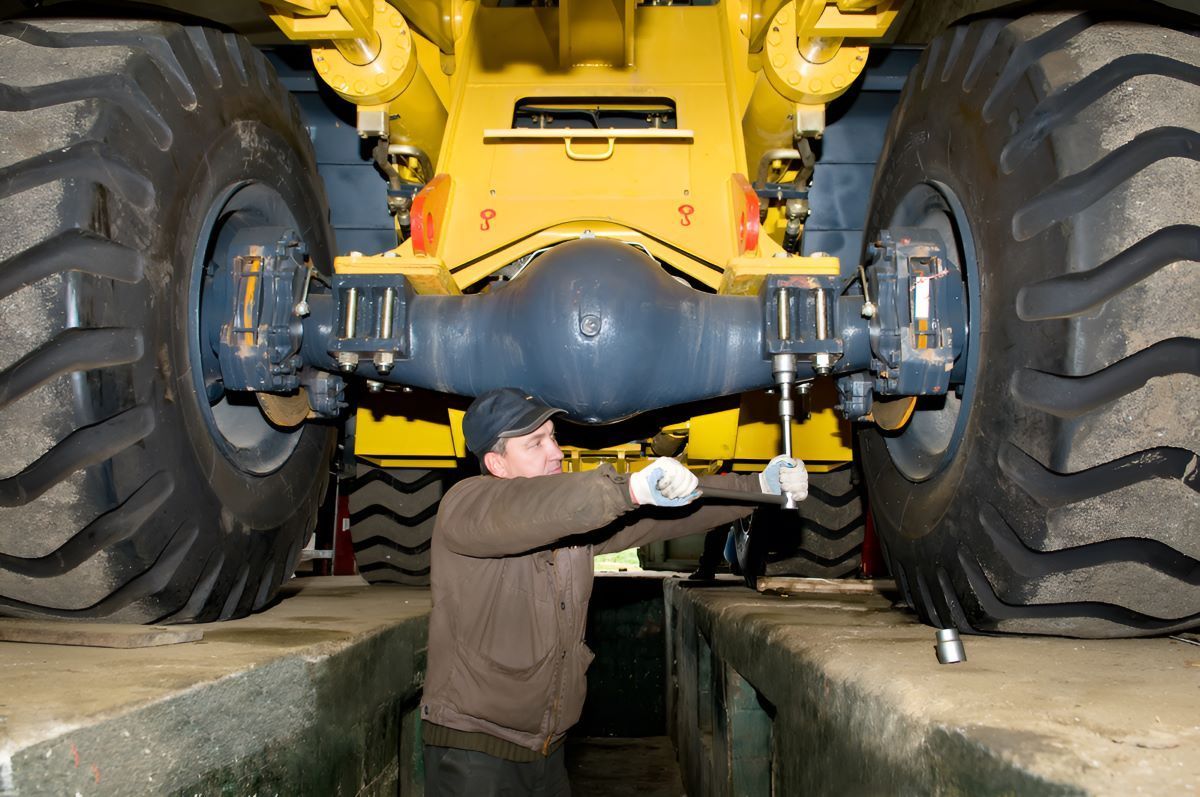 A Man is Working on the Underside of a Yellow Truck — SMK Rural & Mechanical Pty Ltd in Rockhampton City, QLD
