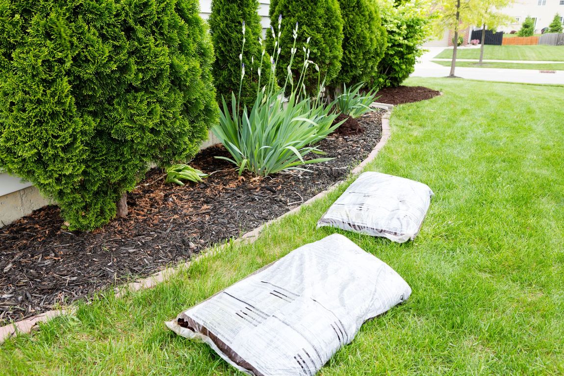 two sacks of mulch are sitting on top of a lush green lawn