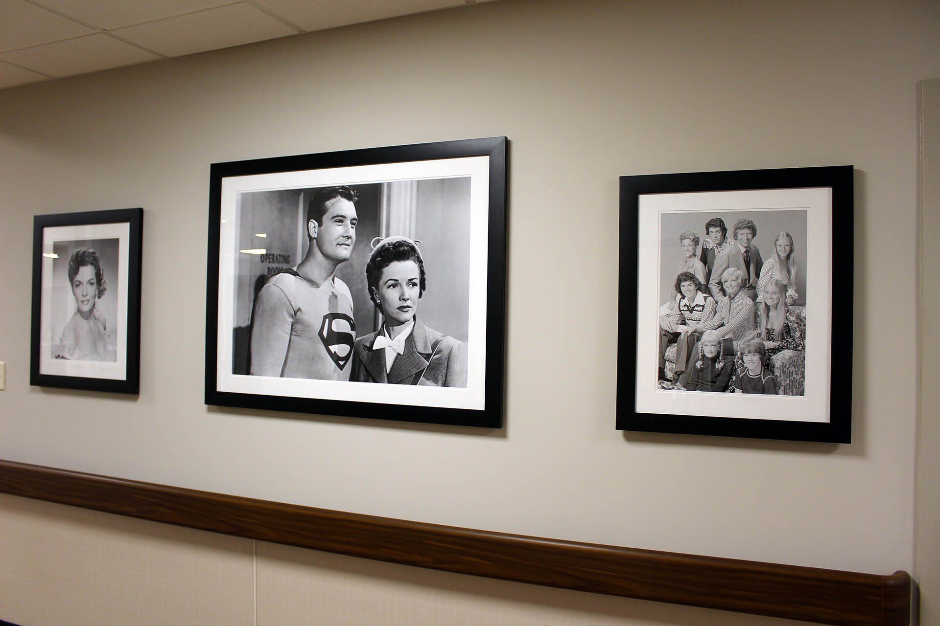 Three framed pictures are hanging on a wall including one of superman