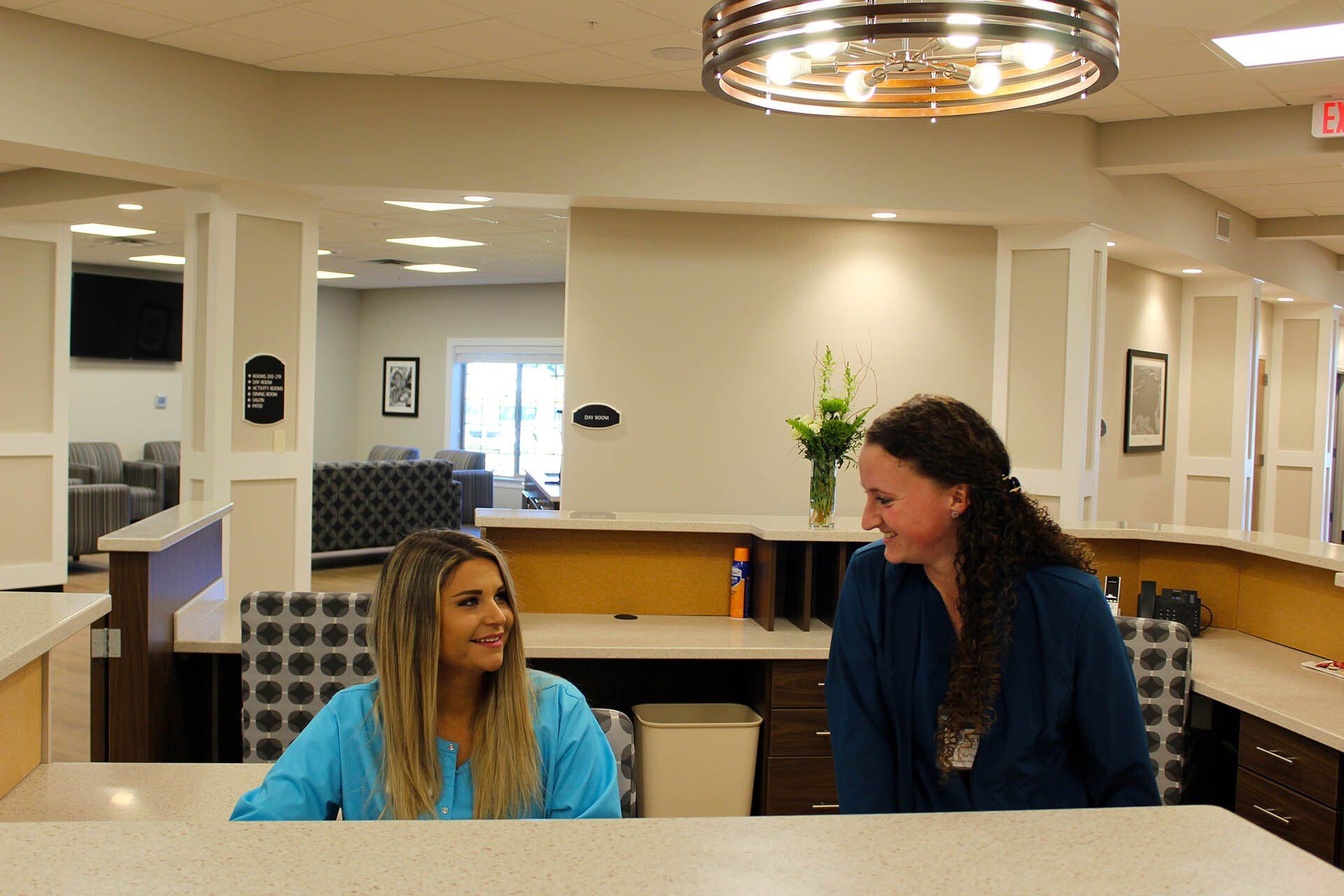 Two women are sitting at a counter in a restaurant talking to each other.