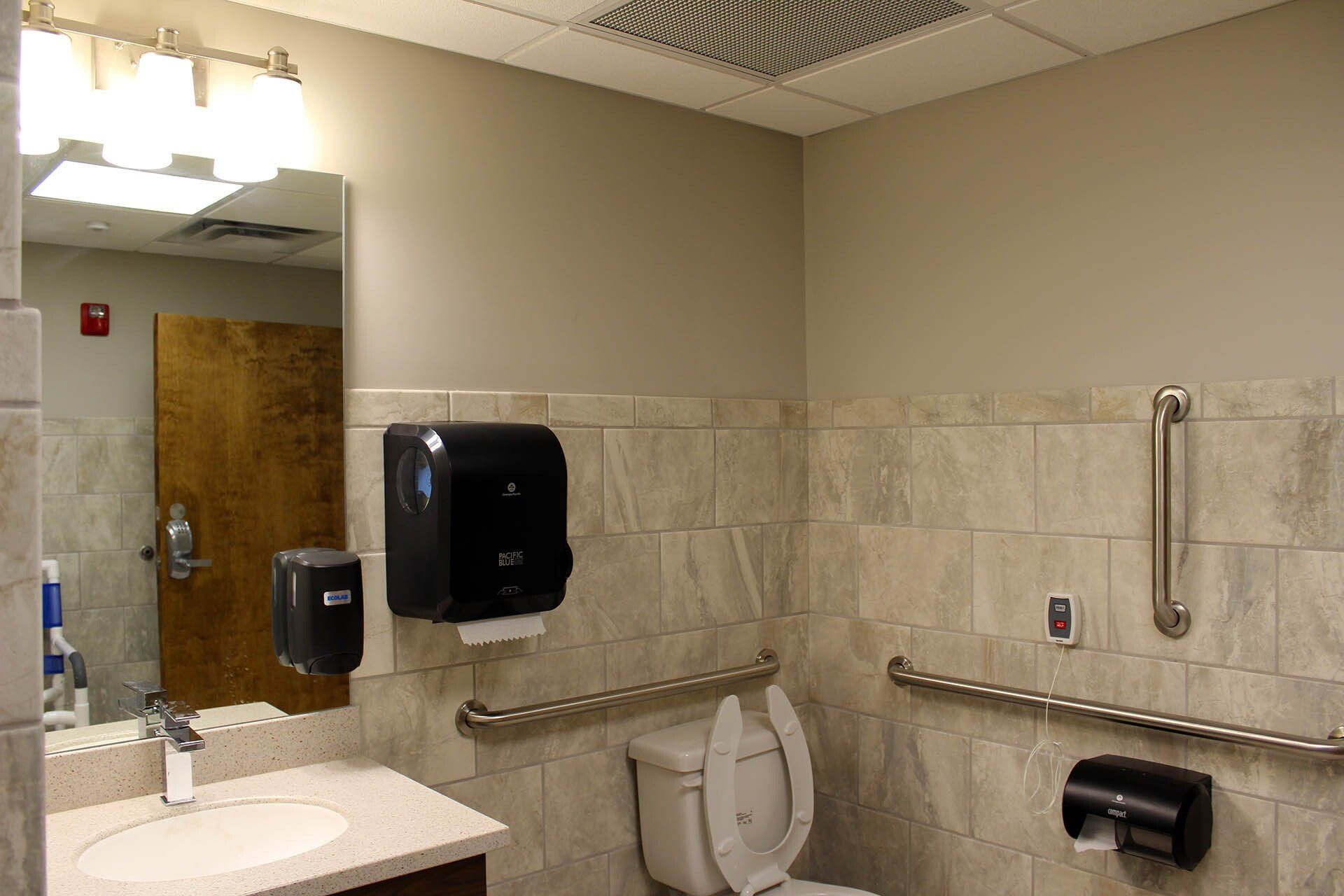 A bathroom with a toilet a sink and a mirror