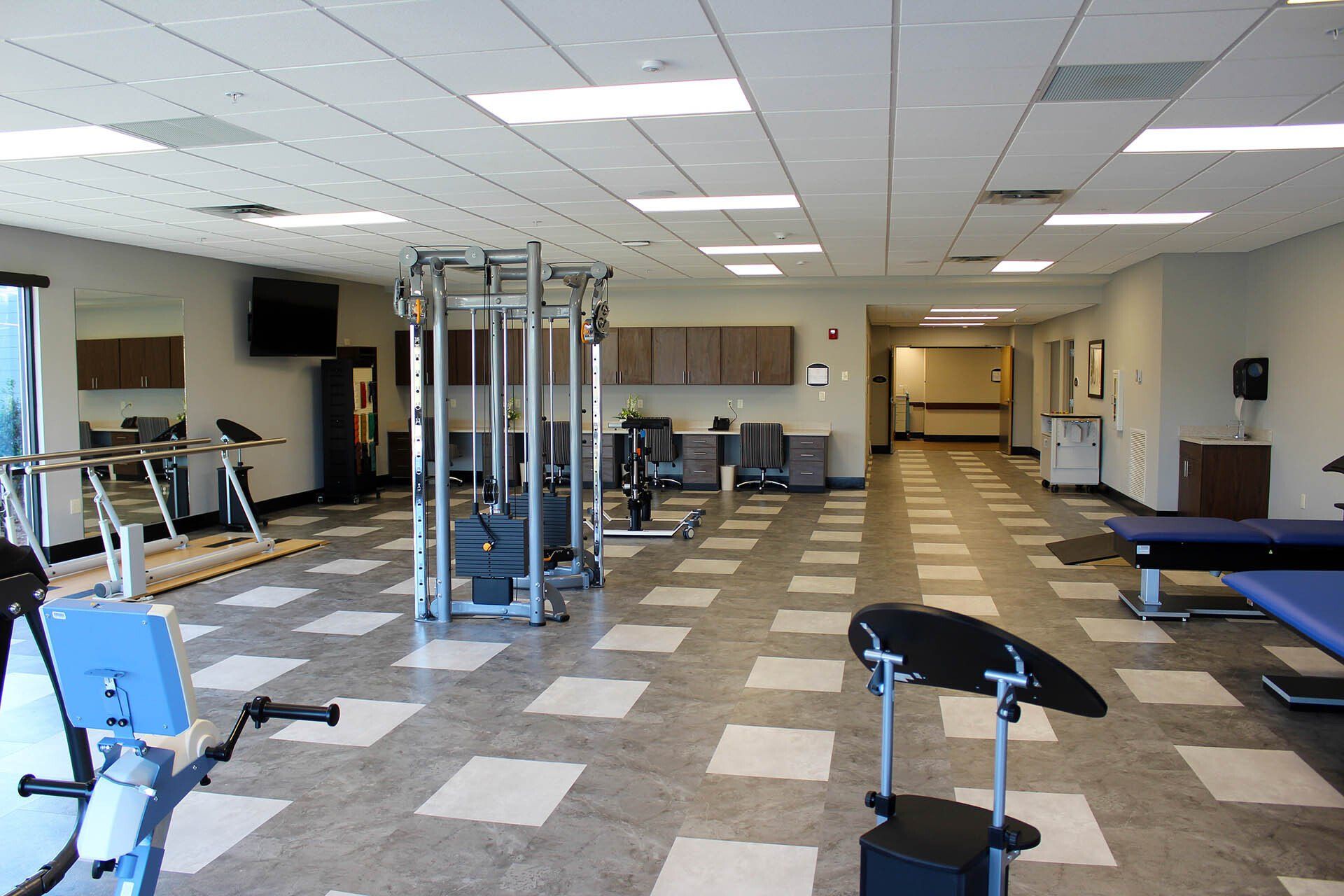 A large gym with a lot of exercise equipment in it.