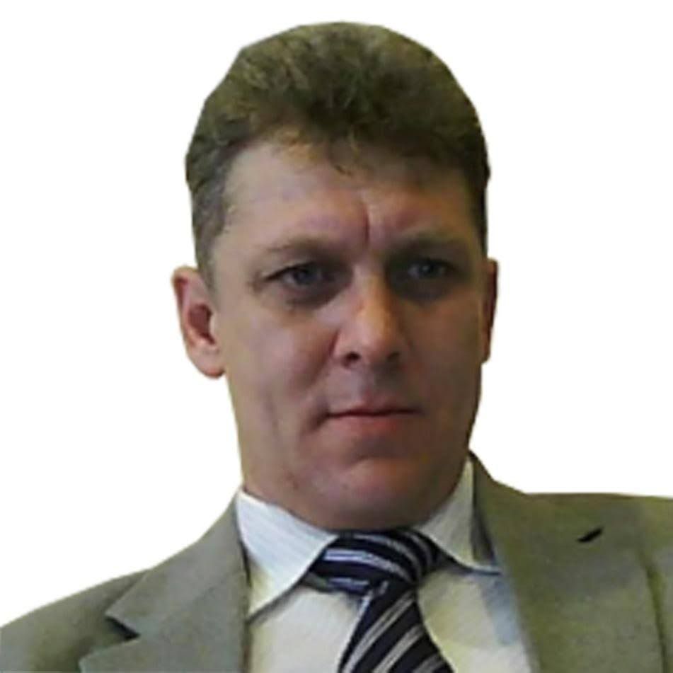 A man in a suit and tie looks at the camera