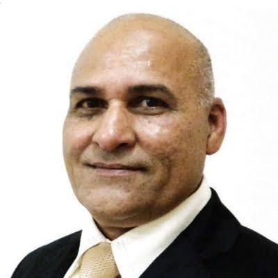 A bald man in a suit and tie is smiling for the camera.