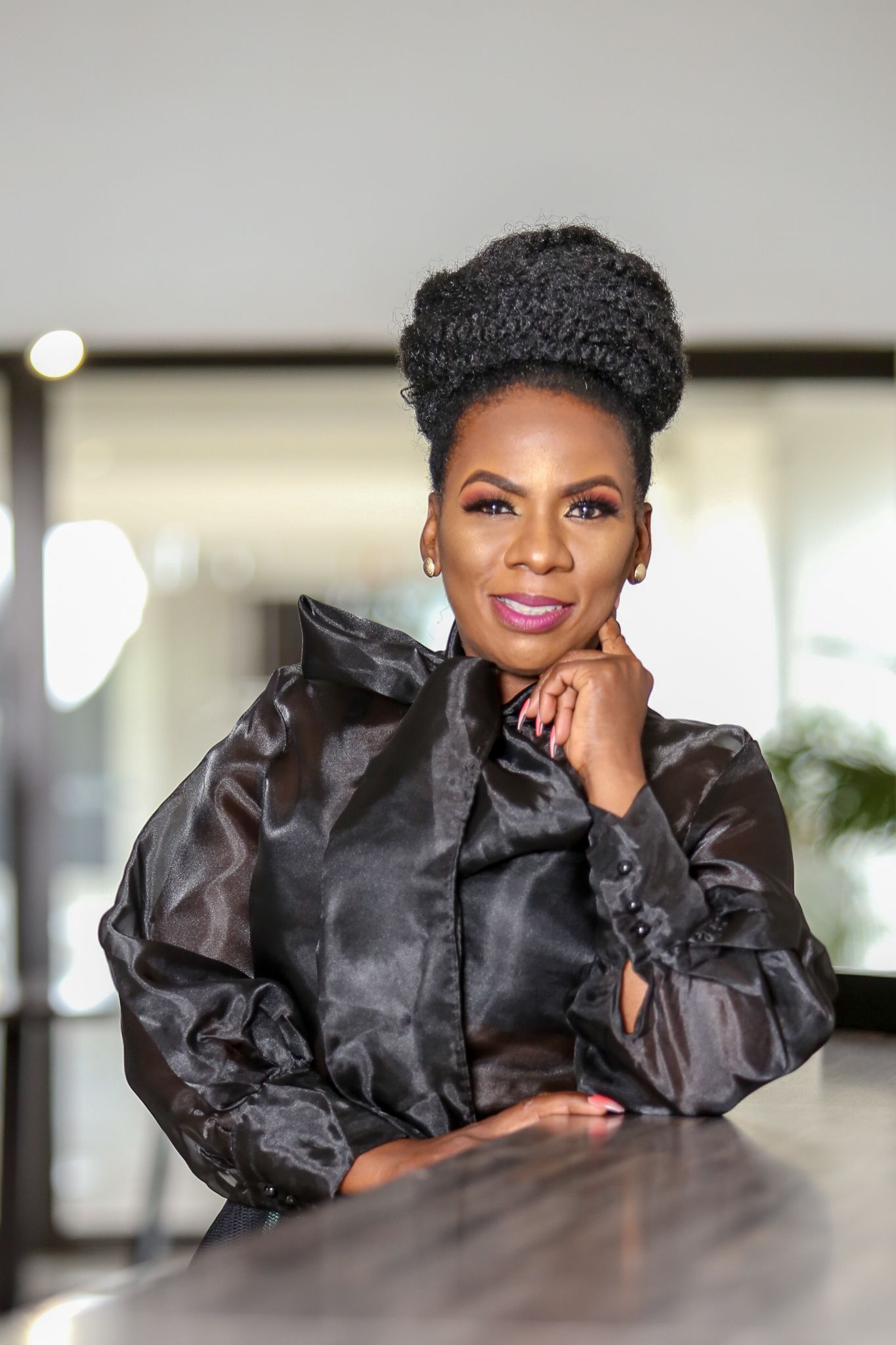 A woman wearing a blue dress and earrings smiles for the camera