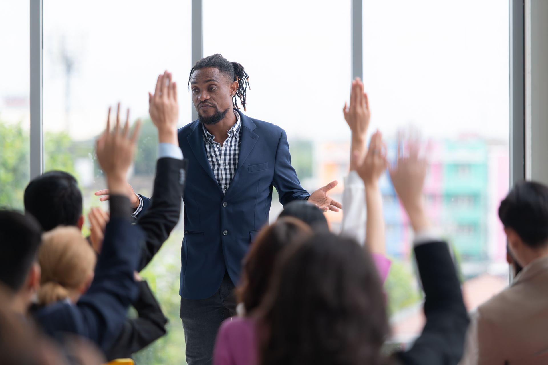 A man is standing in front of a group of people raising their hands.