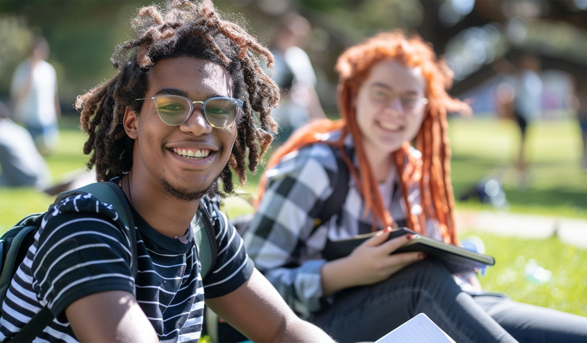A man and a woman are sitting on the grass in a park.