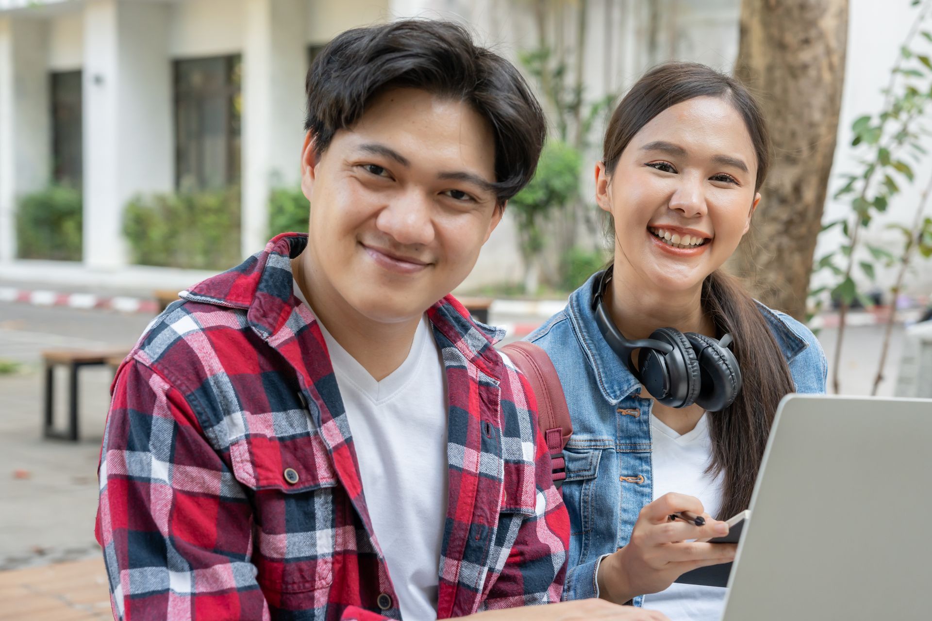 A man and a woman are sitting next to each other in front of a laptop computer.